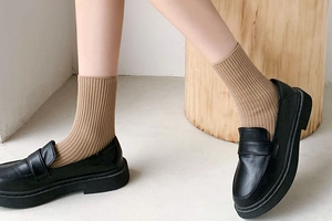 Detail of light khaki ribbed crew socks paired with black leather platform loafers shoes