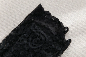 Détail du tissu en dentelle noire avec des motifs ajourés délicats et des bords festonnés