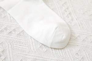 Dettaglio macro delle cuciture e della trama in cotone delle calze a maglia bianche