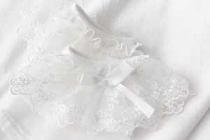 Détail de chaussettes en dentelle blanche avec nœud satiné et broderie florale fine