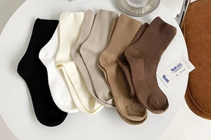 Flat lay of five-color ribbed mid-calf socks in white, black, beige and coffee tones