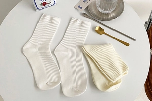 Detailed macro view of white and beige ribbed cotton crew socks with vertical knit patterns