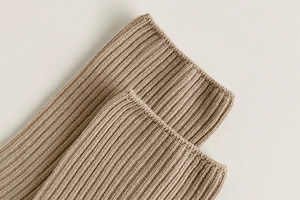 Macro shot of khaki ribbed knit texture on white socks showing fine material detail