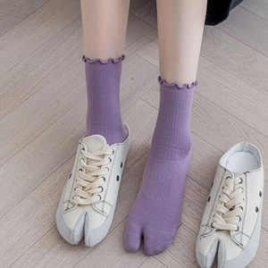 Detail of purple tabi socks with ruffled edges worn with split-toe canvas mule shoes