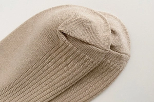 Close-up of beige knit crew socks featuring soft vertical ribbed cotton texture