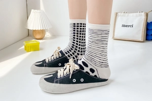 Detail of black canvas mule sneakers paired with stylish striped and polka dot cotton socks
