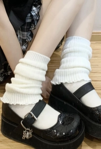 Detailed macro view of black Mary Jane shoes with spider-themed metal charms and white socks