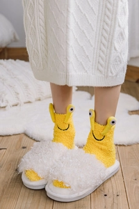 Detail of yellow cartoon fleece socks with plush white slippers on a cozy wooden floor