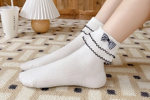 Detail of white Lolita socks with black bow, frill edge and diamond knit texture