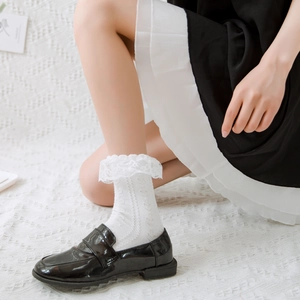 Close-up of white lace trim on cotton socks worn with black loafers in JK style