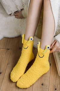 Detail of yellow fuzzy snail socks with cute 3D eyes and soft coral fleece texture