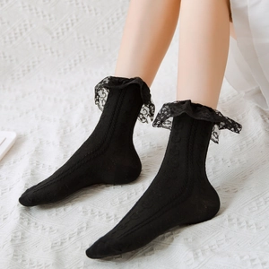 Detail of black JK socks with delicate lace trim and floral knit pattern on white rug