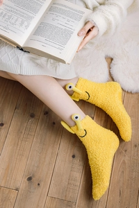 Detail of warm yellow coral fleece home socks with cute 3D cartoon eyes and smiley face