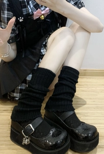 Detail of black ribbed knit leg warmers with chunky Mary Jane shoes and spider charm