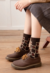 Detail of vintage brown leather shoes with yellow laces and floral checkered wool socks
