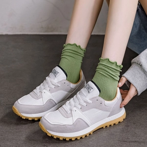 Modern white and grey suede sneakers with ridged rubber soles and ruffled cotton socks