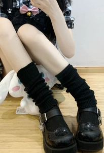 Close-up of black knitted leg warmers showing ribbed texture with gothic shoes