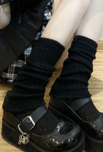 Detail of black ribbed knit leg warmers paired with gothic spider charm Mary Jane shoes
