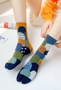 Artistic color-block split-toe socks with abstract geometric prints on a white floor