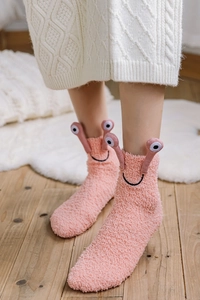 Close-up of pink coral fleece socks with cute cartoon snail eye detail for home comfort