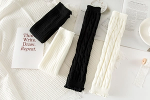 Detailed view of knitted leg warmers in black and white with ribbed and cable knit textures