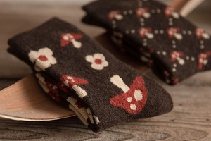 Detailed knit texture of wool socks featuring retro red mushroom and floral patterns