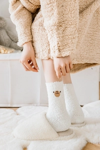 Gros plan de chaussettes en polaire corail beige avec broderie tête d'ours mignonne