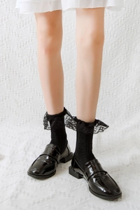 Detail of black lace trim socks paired with shiny patent leather Mary Jane shoes