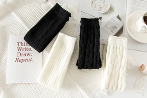 Detailed knit texture of solid white and black leg warmers on a cozy background