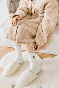 Détail de la broderie ours sur chaussettes d'hiver blanches en polaire avec chaussons