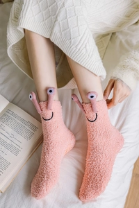 Detail of pink coral fleece sock featuring cute 3D eyes and orange non-slip grip dots