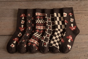 Detail of six thick knitted wool socks with vintage patterns on a rustic wooden background