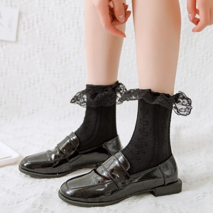 Close-up of black patent leather loafers with delicate black lace trim cotton socks