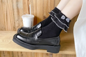 Detailed view of JK style white ruffle socks with bow and black platform loafers