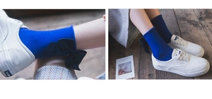 Dettaglio di calze blu reale con grande fiocco nero sul tallone e bordo arrotolato