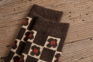 Detailed macro of thick wool socks with retro flower patterns and ribbed cuffs on wood