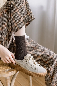 Close-up of beige platform sneakers styled with wool socks and plaid pants for autumn