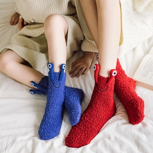 Close-up of fluffy coral fleece socks in red and blue with cute 3D cartoon eyes