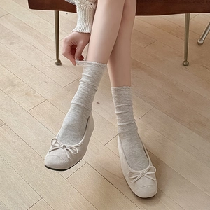 Detailed view of beige ballet flats paired with vintage grey jacquard crew socks on wood