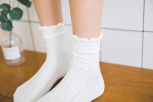 Detailed knit pattern and scalloped edges of white cotton mid-calf socks