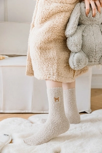 Gros plan d'une broderie d'ours sur des chaussettes thermiques douces en polaire beige