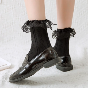 Close-up of black lace ruffle socks with heart knit pattern and patent loafers