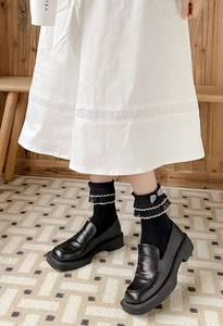 Detail of JK style black mid-calf socks with white lace trim and striped bow decoration