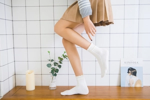 Detail of white cotton mid-calf socks with vertical knit texture and ruffle lace cuffs
