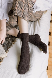 Detailed knit texture of dark coffee wool socks with diamond pattern in cozy setting