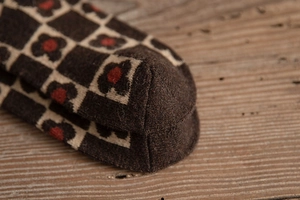 Macro detail of thick knitted wool sock showing retro flower checkerboard pattern texture