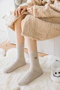 Gros plan sur des chaussettes d'hiver en polaire corail avec broderie ours en beige