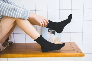Detailed view of black ribbed mid-calf socks with delicate ruffle trim and cotton knit texture