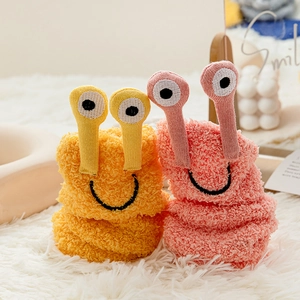 Close-up of soft coral fleece cartoon socks with 3D eyes on a cozy plush background