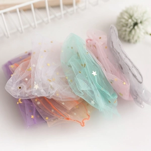 Close-up of sheer mesh scrunchies with gold star and moon patterns in pastel colors